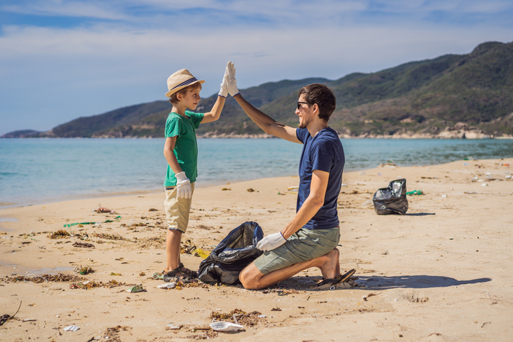 Father and son high-fiving after cleaning up the beach