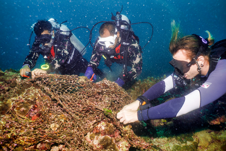 Clean Coast Crew volunteers scuba diving and working to remove a net that is caught on a reef